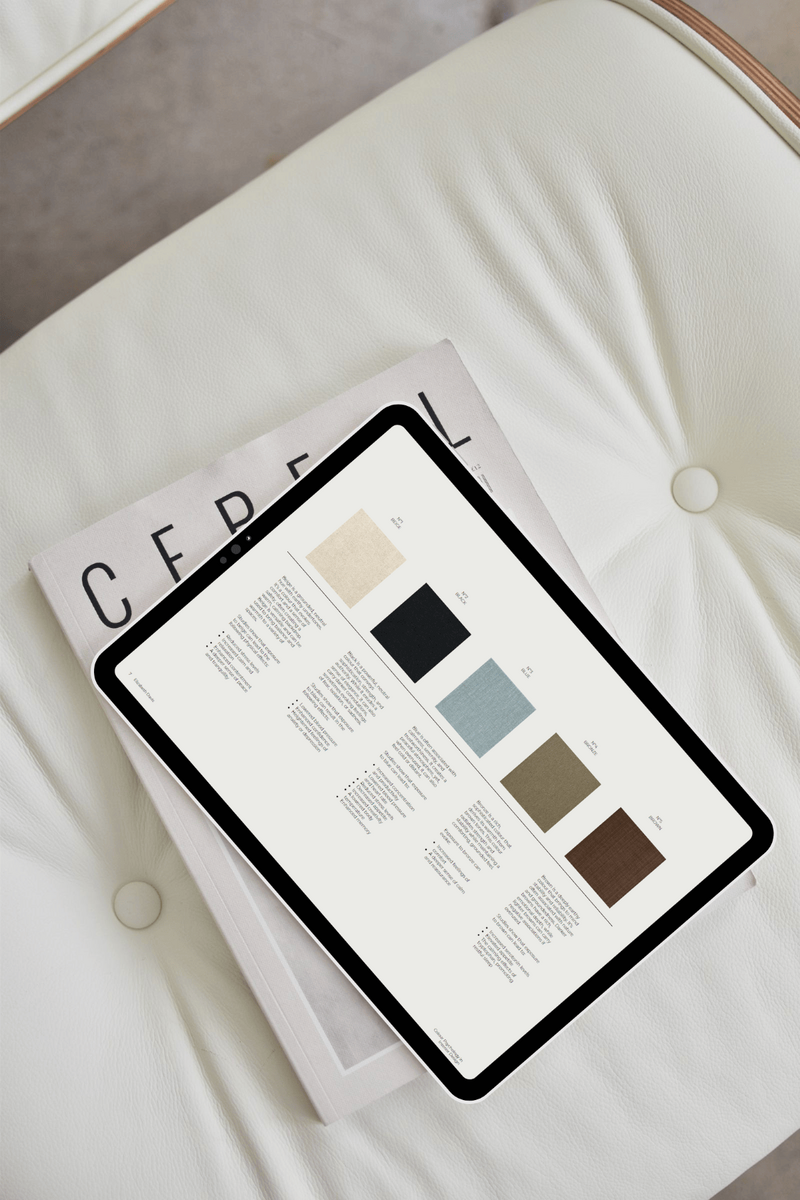 A cream leather chair with a book and an iPad resting on the seat cushion. The iPad displays a page from my Colour Psychology in Interior Design guide, a free resource available on my website.
