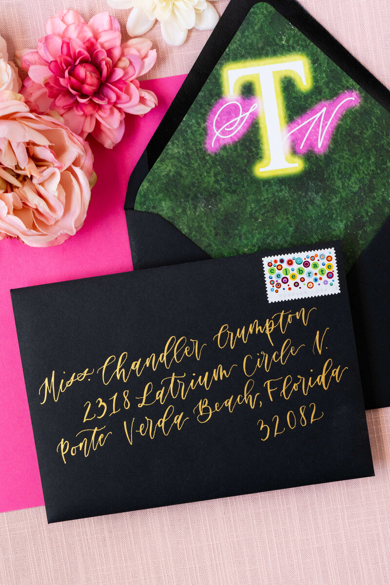 contemporary wedding stationery in bold black and hot pink, highlighted by elegant gold calligraphy and a unique postage stamp