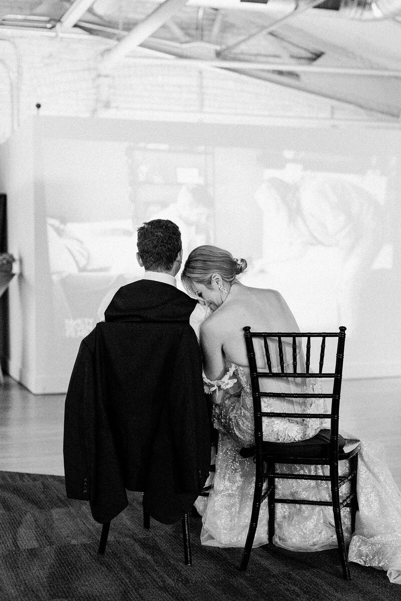 Couple watching same day wedding film during wedding reception at Baker Lofts Downtown Holland.