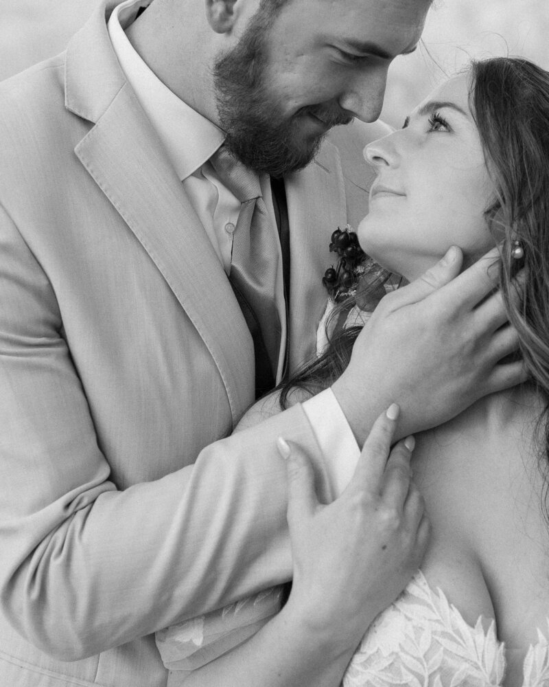 bride hugging the back of her grooms neck surrounded by red rock formations in Utah at sunset