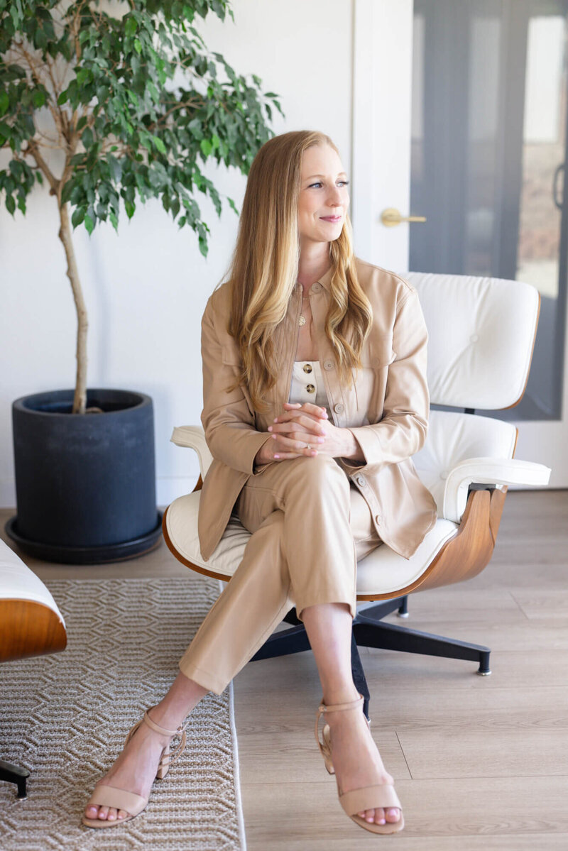 Mary Pernicano, San Diego listing agent, sitting in a modern chair and holding her phone during a home consultation — Mary Pernicano Real Estate.