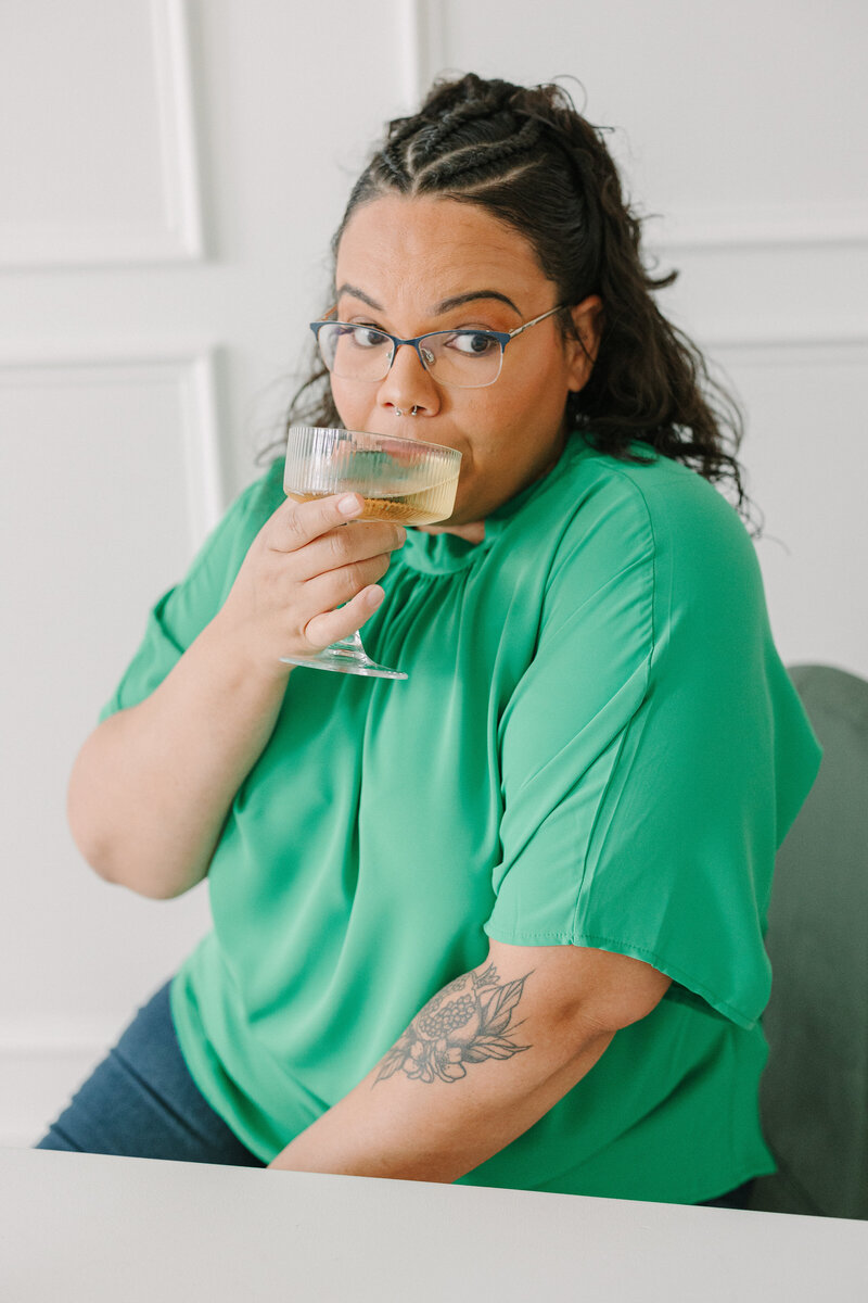 A person sitting and sipping from a cocktail glass