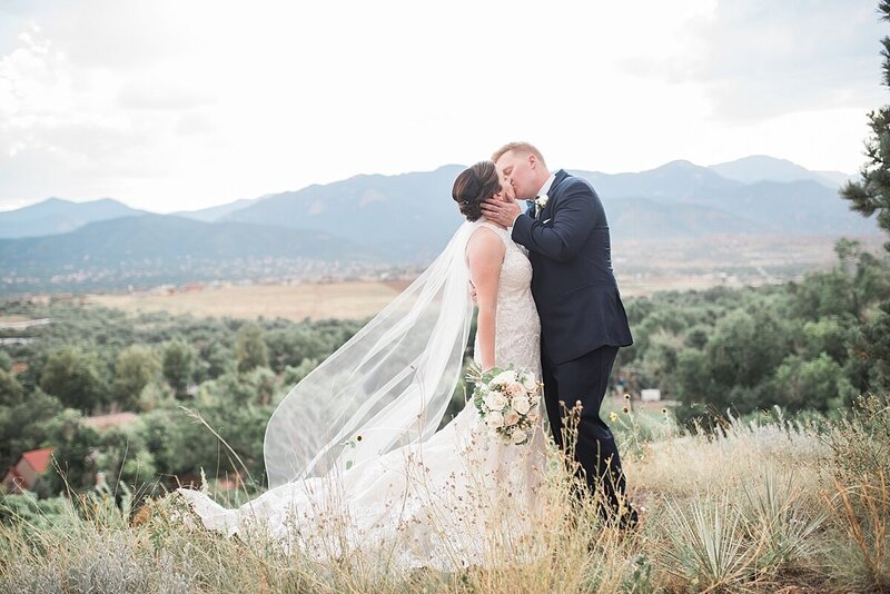Couple kissing in front of the mountains at The Pinery wedding venue in Colorado Springs