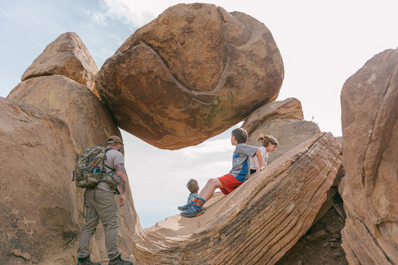 Documentary family photo at Balanced Rock in Big Bend National Park, featuring rugged desert terrain and editorial composition with movement and emotion.

