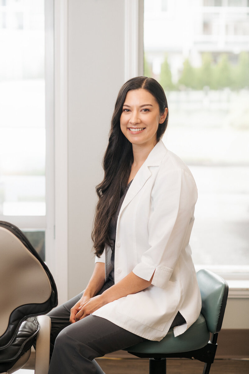 Dr Heather Dagenais leaning on a glass door with her arms crossed and smiling