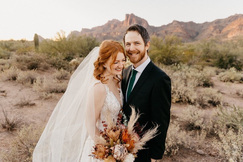 Playful couple giggling in the Phoenix desert with the superstition mountains behind them