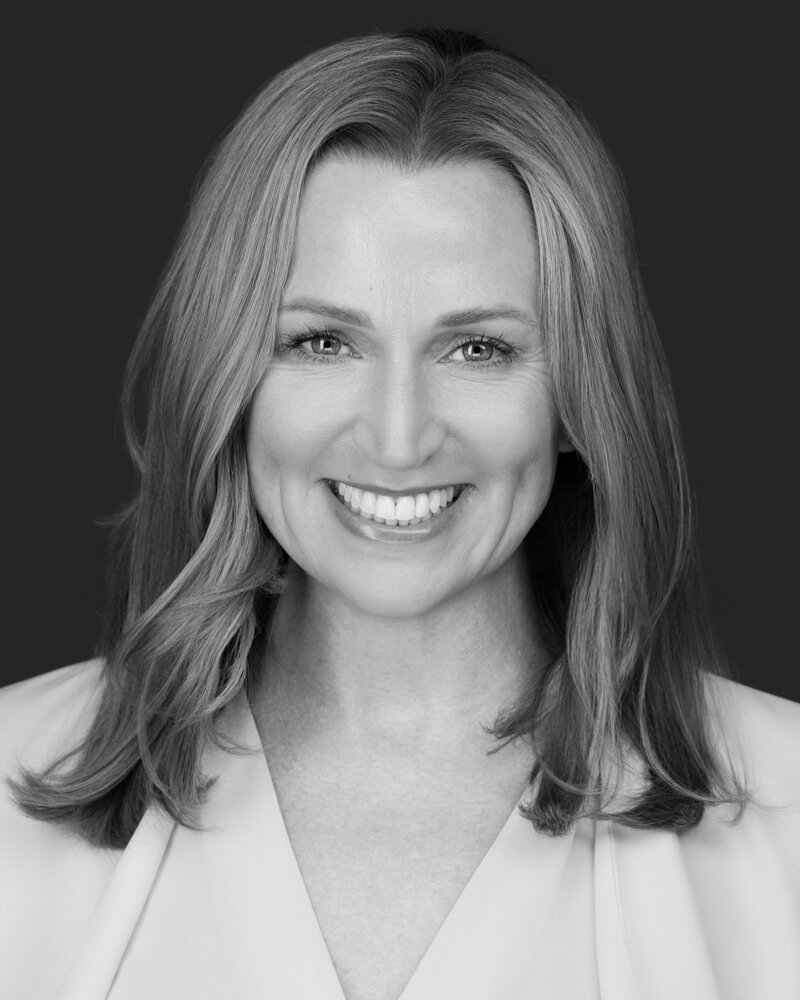 Jenn Cloutier professional black and white headshot with warm smile and shoulder-length blonde hair, wearing light-colored blazer.