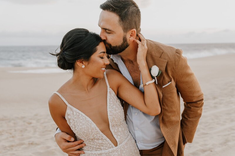 bride and groom embrace on beach after wedding ceremony in san diego
