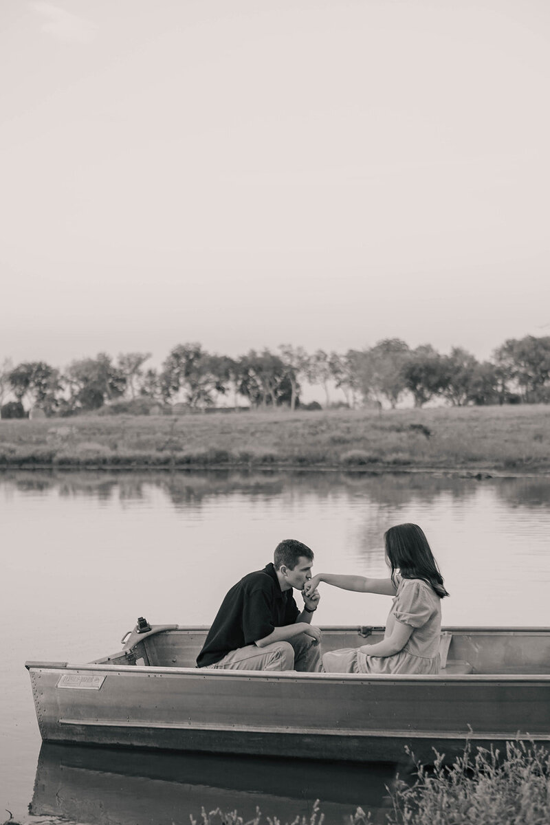 man kissing fiance's hand on a row boat in dallas texas