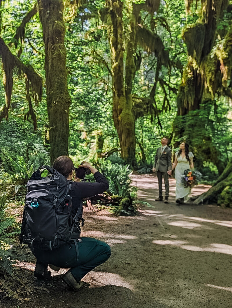 Sage Trails Crouching taking photos of a an eloping couple in the Hoh rainforest.