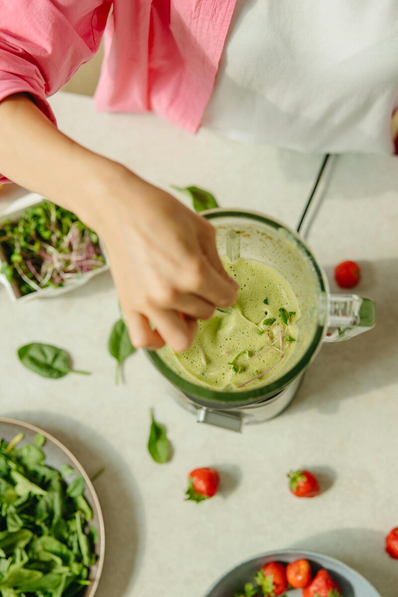 Top view of a woman making a green smoothie