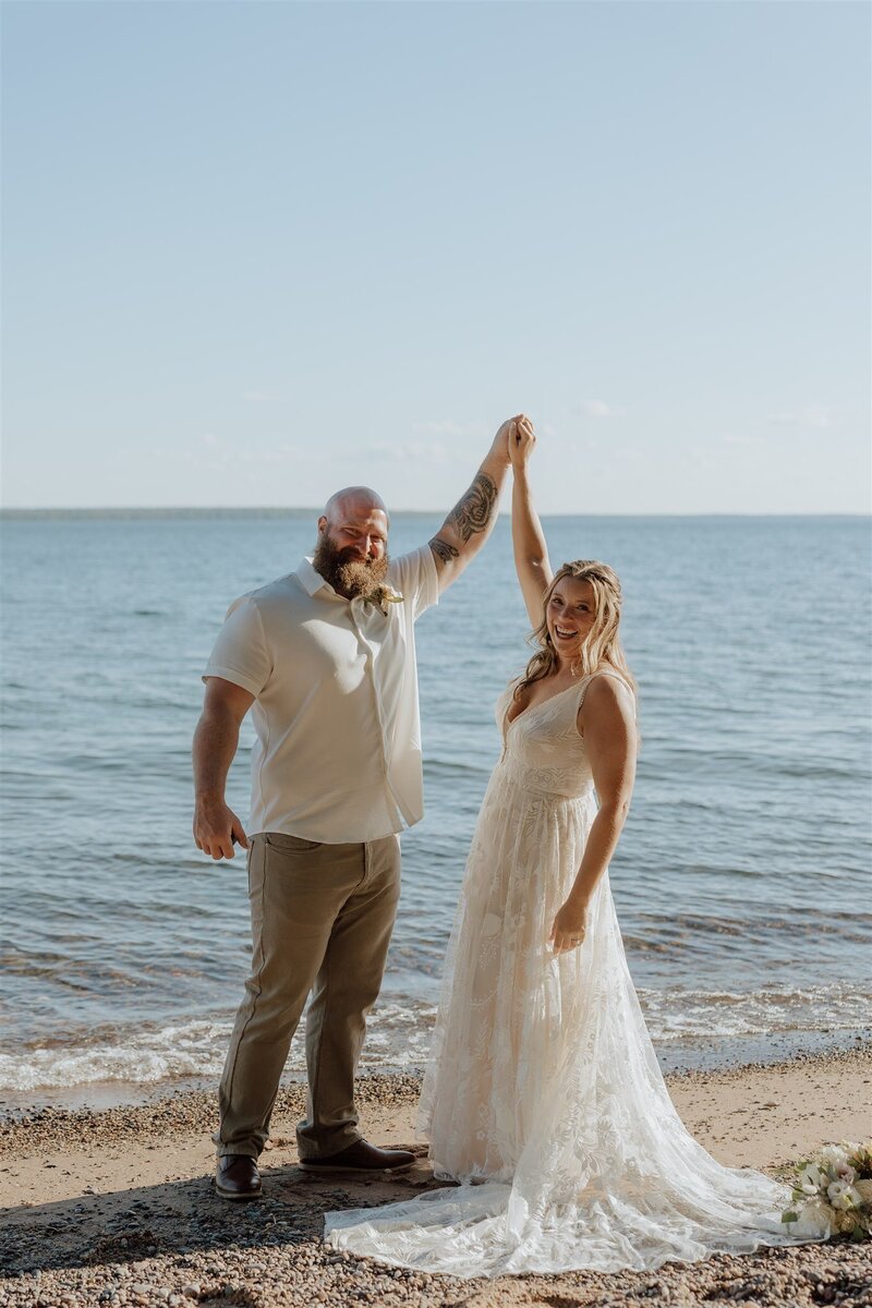 elopement in Wisconsin at the apostle islands. Bride and groom are celebrating on a beach after getting married