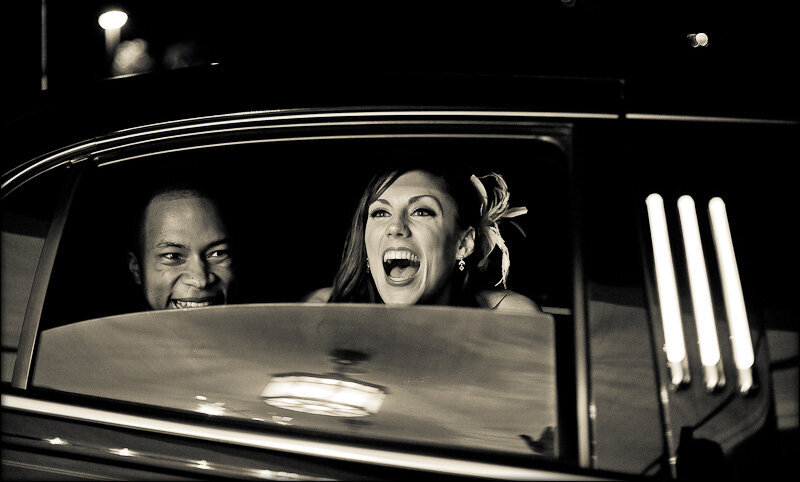 Bride and groom smiling in their limo in black and white