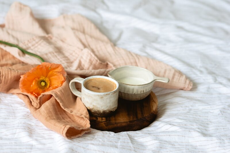 mug sitting on a wooden tray surrounded by a blanket and a poppy