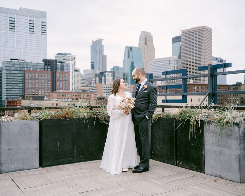With the Minneapolis skyline in the background, look lovingly at each other before their Hewing Hotel wedding.