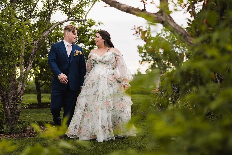 Couple walking in a garden surrounded by greenery.