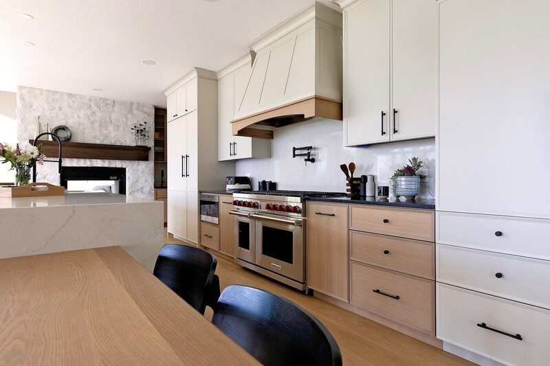A mix of white and light wood cabinets with sleek black fixtures and white counter tops.