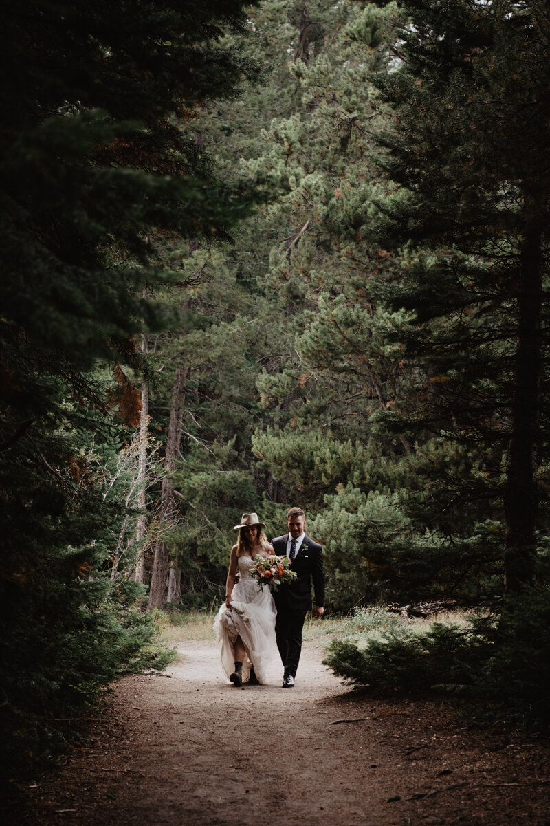 adventurous wyoming elopement pictures with bride and groom walking through a forest trail in the Grand Tetons captured by jackson hole photographers