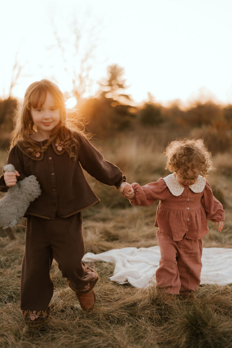 girl holds little sister's hand during family photos in peoria il