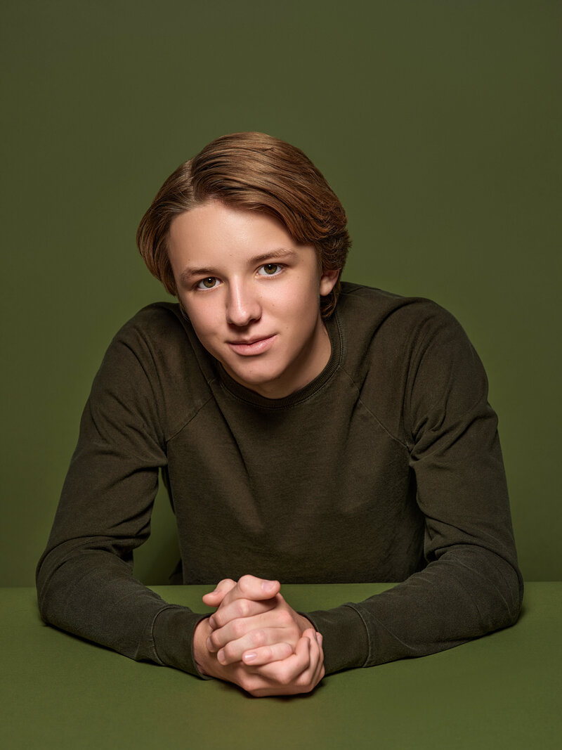 A teenager smiling with his hands clasped