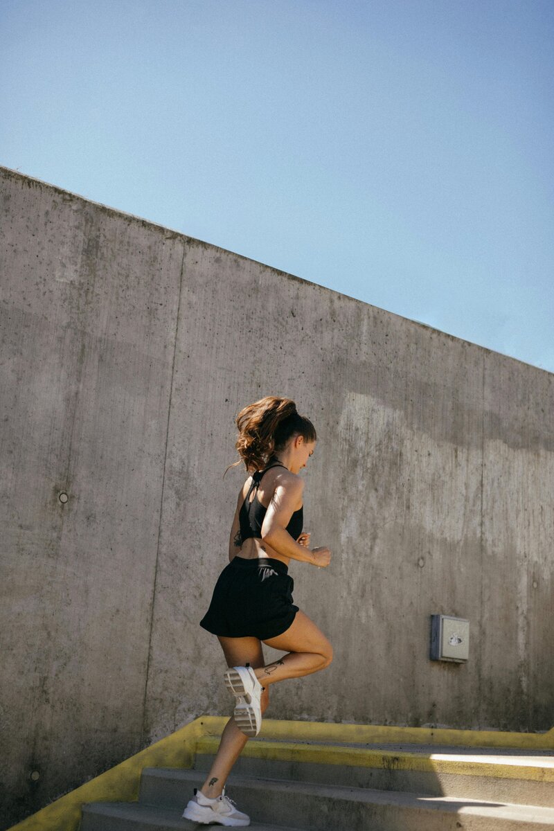 a woman with a high ponytail running up stairs