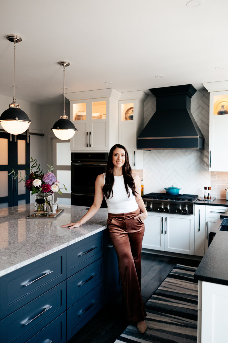 Full body view of woman standing in kitchen and leaning against the island