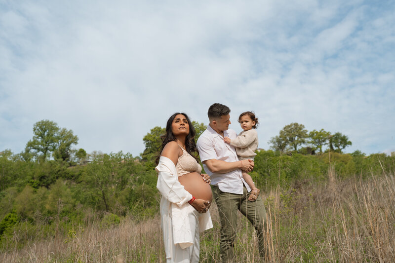 mom standing pregannt with husband and son in field 