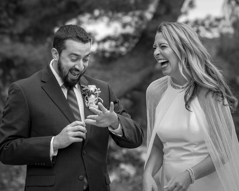 Bride and groom laughing together while admiring their wedding rings during their elopement in Valley Forge Park.
