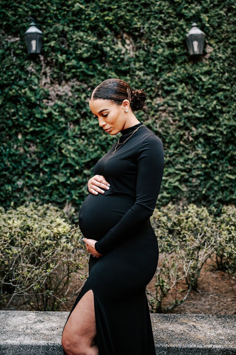 Pregnant mom in black dress at a vine wall near Orlando, FL
