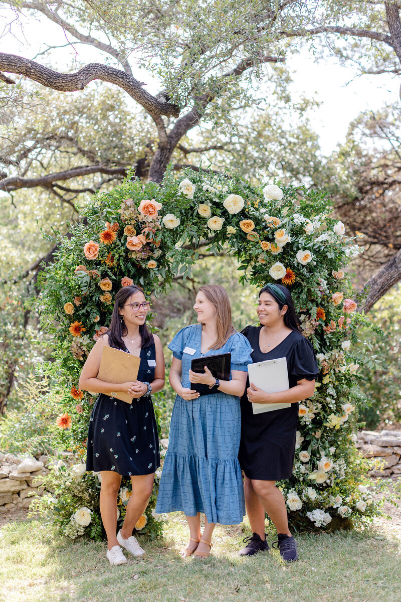 Austin Texas wedding planners smile under an orange floral arch