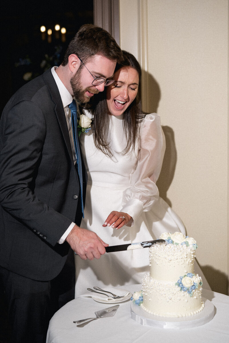 Bride and groom joyfully cutting cake captured by Cleveland Ohio wedding photographer