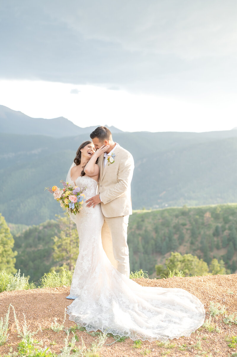 Bride bringing her hand up to the groom's face to snuggle in close while laughing together 