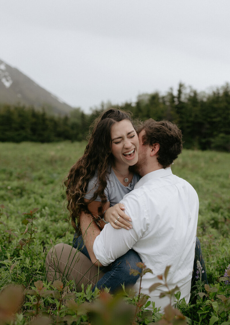 Woman sitting on mans lap in a field of flowers.