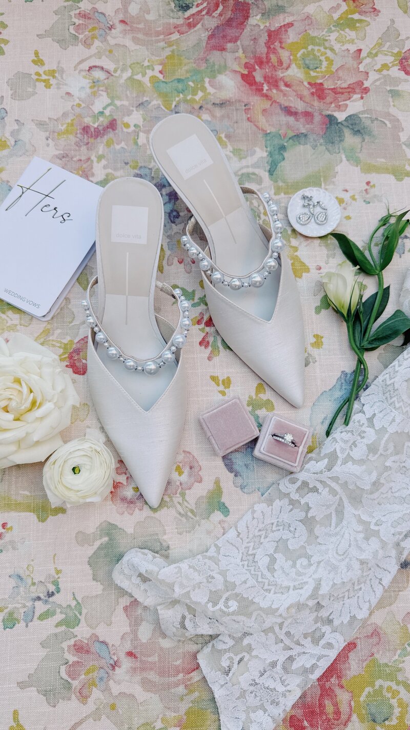 Classic white and gold wedding reception details with white rose floral centerpieces and tapered candles on each table in the ballroom of La Valencia Hotel.