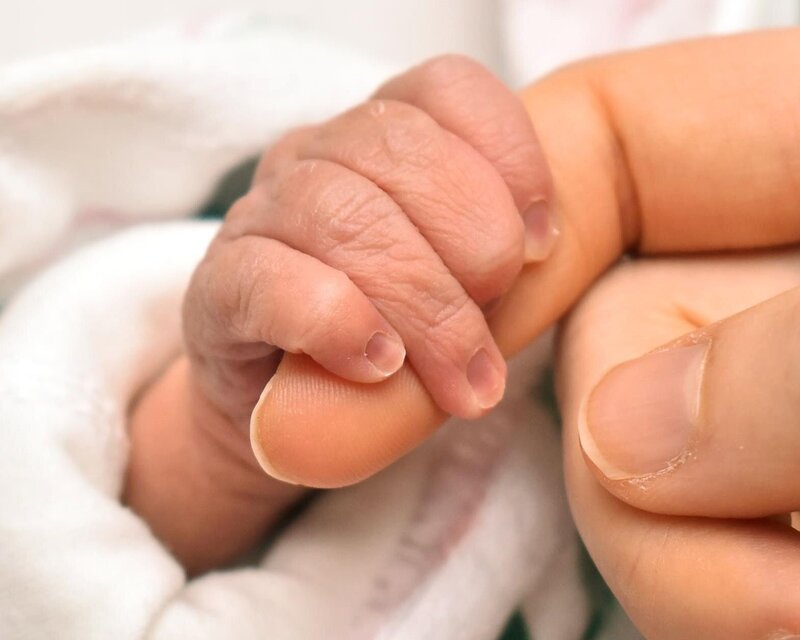 new born fingers holding mother's finger.