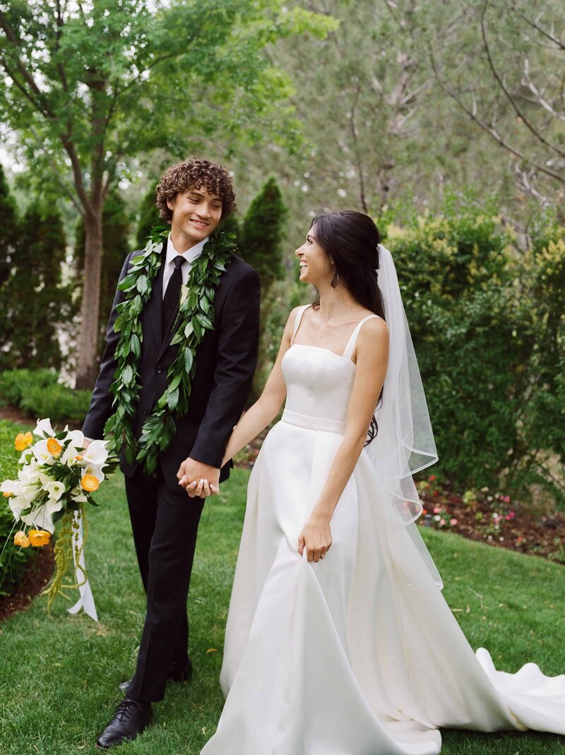 Bride and groom walking holding hands in the garden at a Utah wedding shot on film
