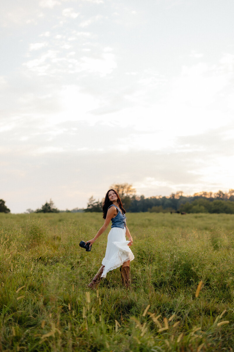 Woman walking through field with camera in her boots