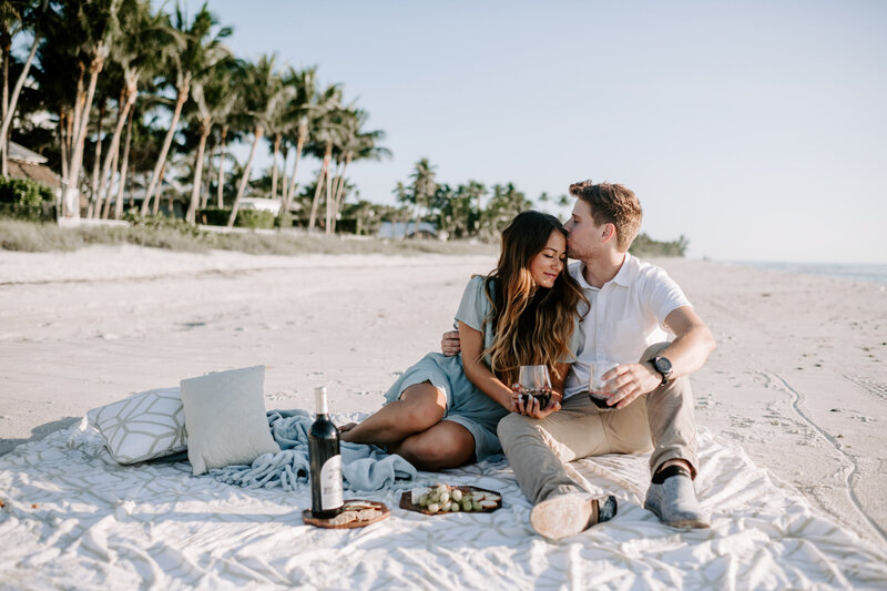 man and woman sitting on beach with picnic