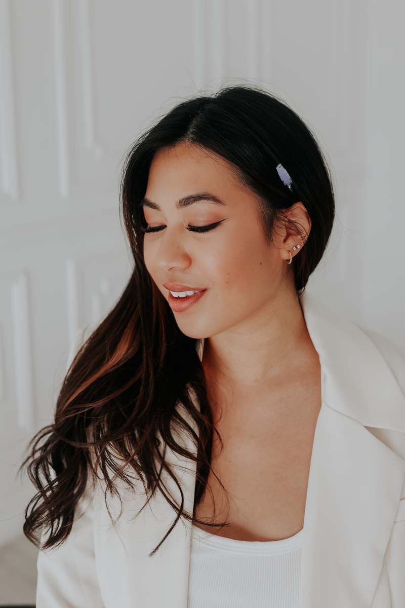 woman in white suit turned to the side and smiling looking down. 