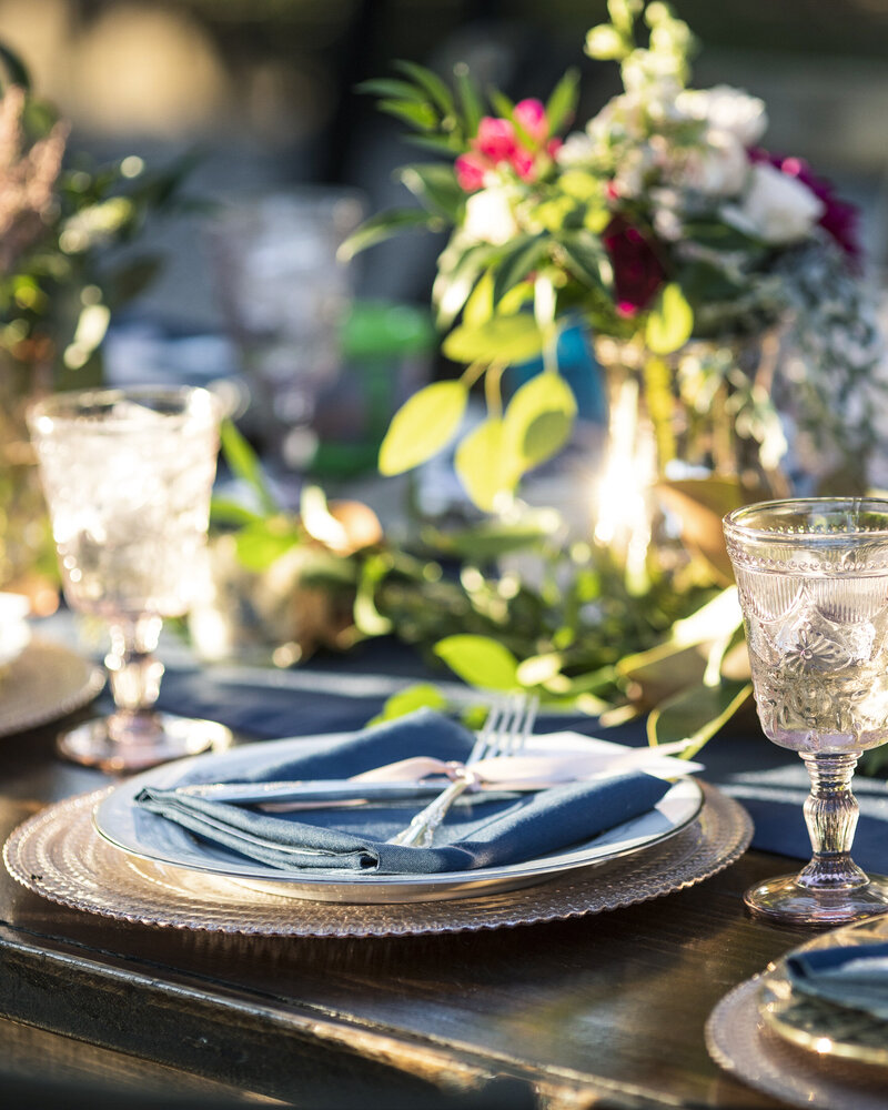 Vintage table setup for outdoor wedding reception with blue napkins