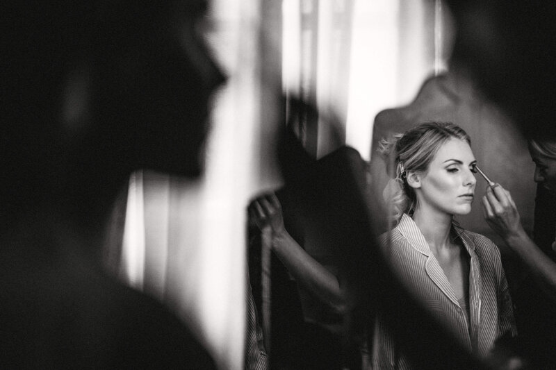 A black and white photo with a reflection in the mirror of a bride getting ready for her wedding