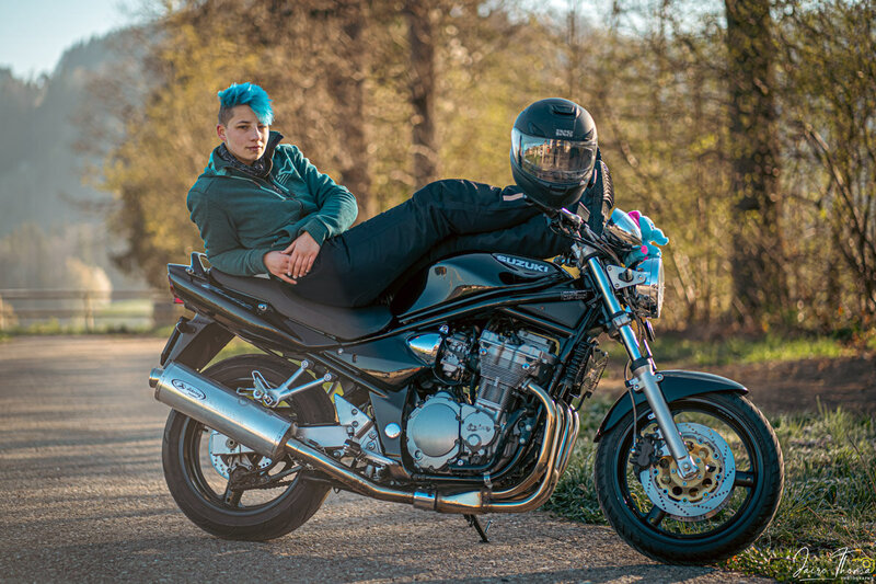 Ein weibliches Model strahlt Verführung und Coolness aus, während es auf einem Motorrad liegt. Ein fesselnder Moment der Stärke.