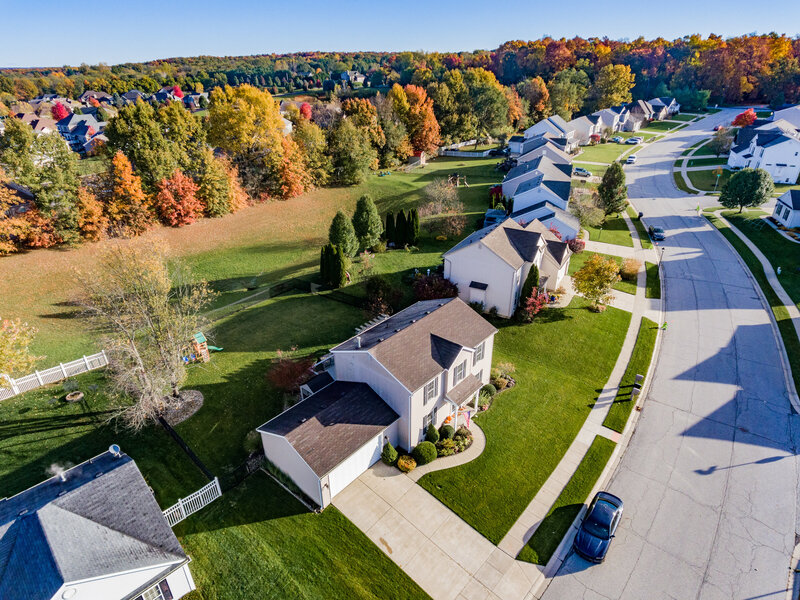 A breathtaking aerial drone shot capturing a beautiful neighborhood bathed in sunlight. The image showcases the layout, architecture, and vibrant atmosphere of the community on a perfect day.