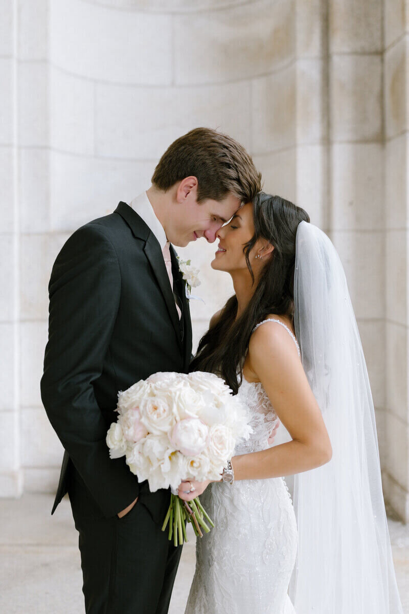 Bride and groom embracing in wedding venue holding wedding flowers by minneapolis wedding florist