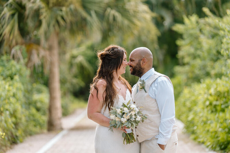 A couple on a path with palm trees shares a private moment at their Cozumel wedding