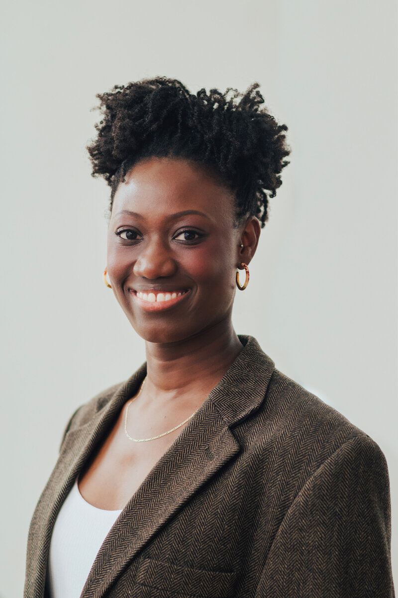 Photo of Linda Mensah smiling into the camera  in front of a neutral background