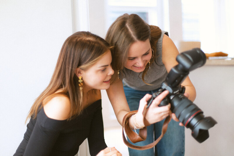Photographer Bo Eppink enthusiastically showing camera settings to Eloise van Oranje during a hands-on photography session, reflecting the educational aspect of their collaboration.