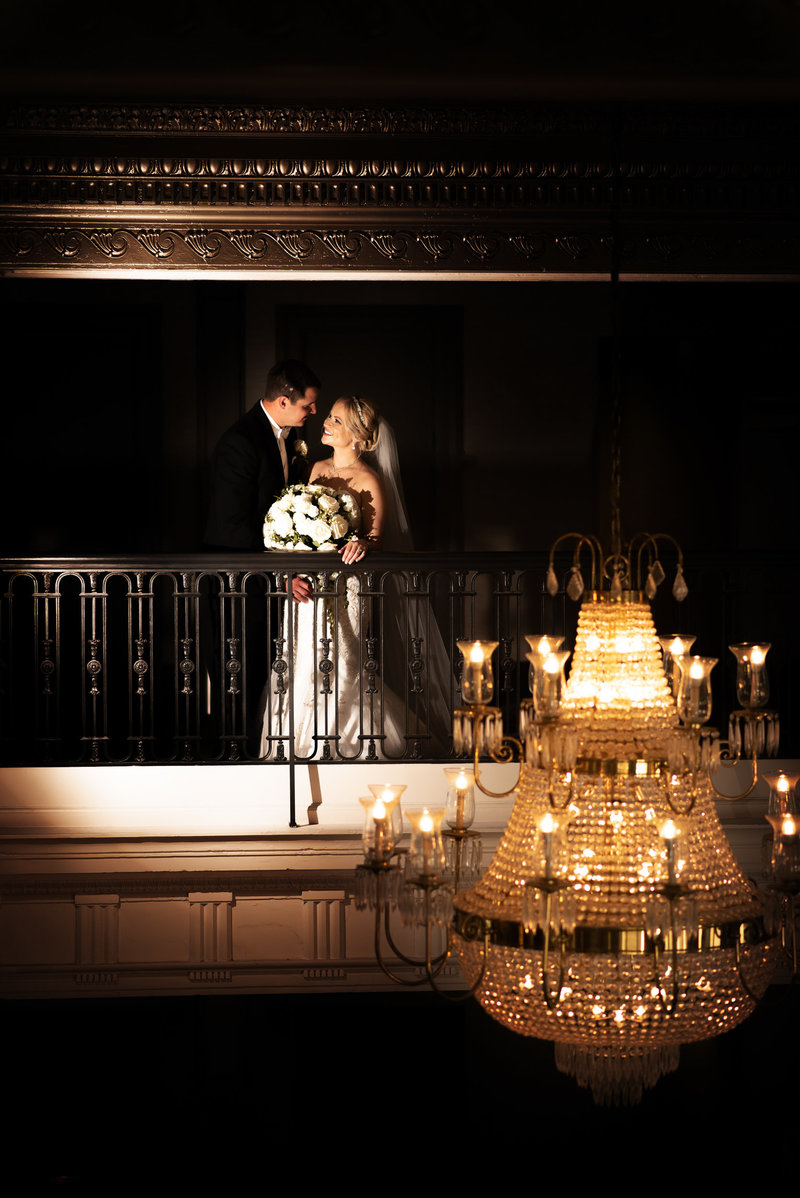Bride and groom portrait with gold chandelier in the foreground