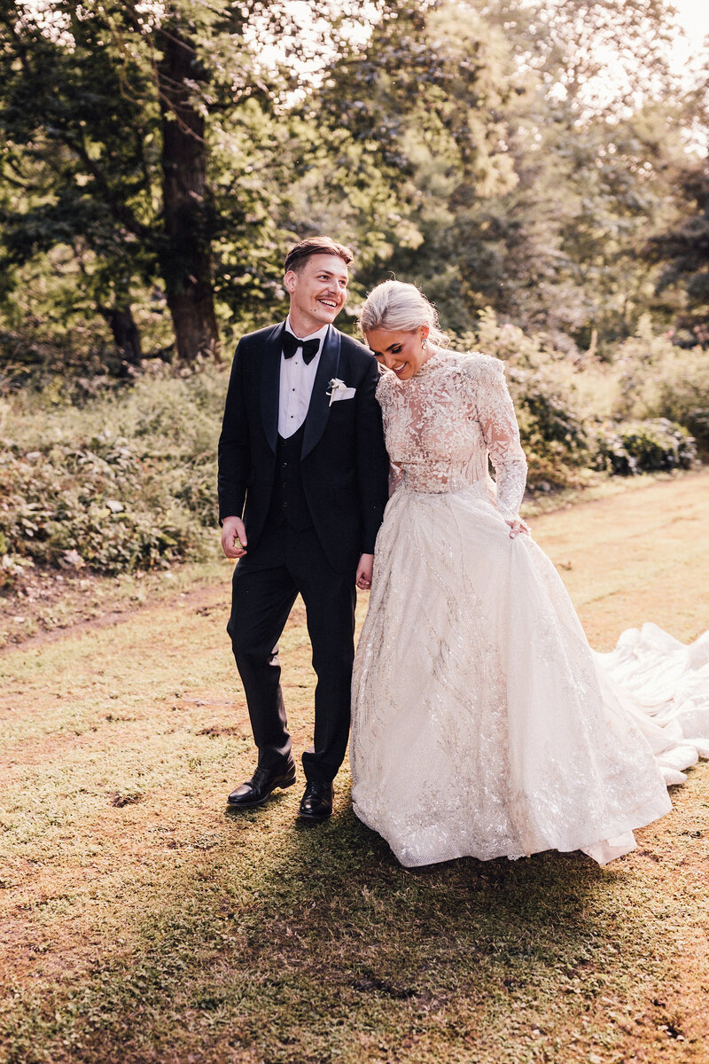 A couple walk hand in hand on the lawn of their destination wedding venue chateau du queille south of france
