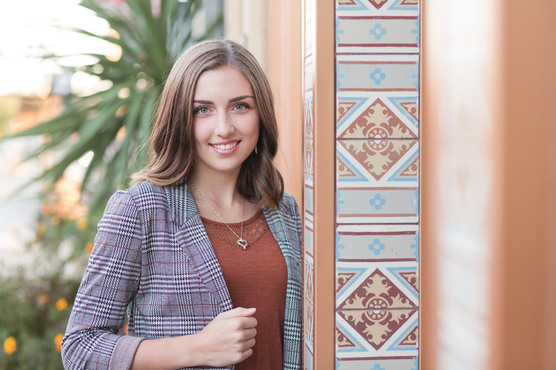 senior girl standing with her arm leaning into the art find tile building, fall colors in the tile mateched her rust colored shirt for fall, photographed by jamie lynette photography canton ohio senior photographer